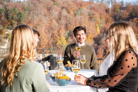 Apéro auf der Schlossterrasse von Schloss Burgdorf: Eine kleine Gruppe geniesst bei herbstlicher Kulisse Wein und Snacks. Die sonnige Terrasse bietet einen einzigartigen Rahmen für private Feiern und Business-Events.