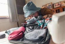 A schoolgirl packs a suitcase for a school camp