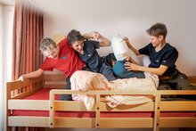 Drei Buben einer Schulreise sind auf einem Etagenbett und haben Spass bei einer Kissenschlacht