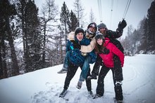 Vier Freunde / Young Traveller haben Spass im Schnee. Zwei sind Huckepack.