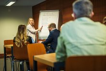 Personen-sitzen-in-einem-Seminarraum-und-hören-einer-Präsentation-zu