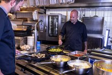 In der Küche stehen zwei Köche und bereiten Essen zu.