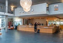 Die weitläufige Rezeption der Jugendherberge Lausanne. Eine Frau ist gerade dabei, einzuchecken.