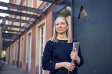 A woman with a laptop is standing in front of Basel Youth Hostel.