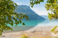 Sandstrand mit Zugang zum Brienzersee und Berge im Hintergrund.