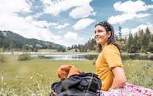 Sina Candrian geniesst eine Pause auf eine grüner Wiese während der Wanderung in Gstaad.