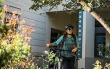 Frau ist mit Bike vor Eingangsbereich der Jugendherberge Locarno.