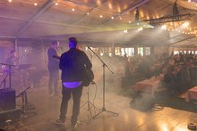 Auf der Bühne vom Jubiläumsfest der Schweizer Jugendherbergen stehen mehrere Musiker. Man sieht sie von hinten. Vor ihnen sitzt das Publikum. 