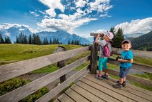 Zwei Kinder schauen auf den Zwergenweg Muggestutz in ein Fernrohr und geniessen den Ausblick.