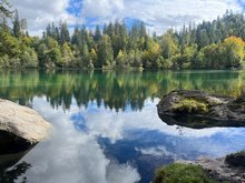 Die herbstlichen Bäume im Hintergrund spiegeln sich im Crestasee.