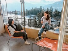 Zwei Frauen sitzen auf dem Balkon der Jugendherberge Crans-Montana.